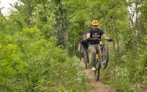 Members of the Evansville community enjoying the miles of mountain bike trails winding through the woods surrounding USI.