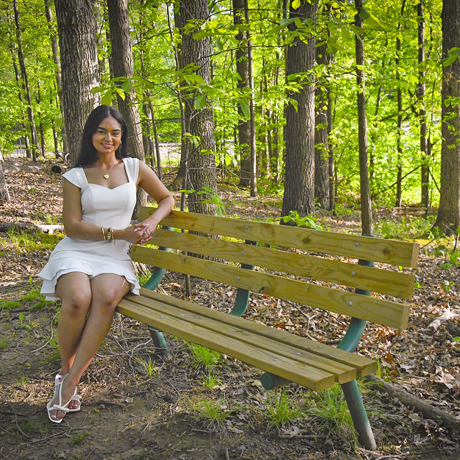 A 2025 graduate sits on one of the benches of the Meditation Trail at USI. 