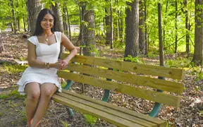 A 2025 graduate sits on one of the benches of the Meditation Trail at USI. 
