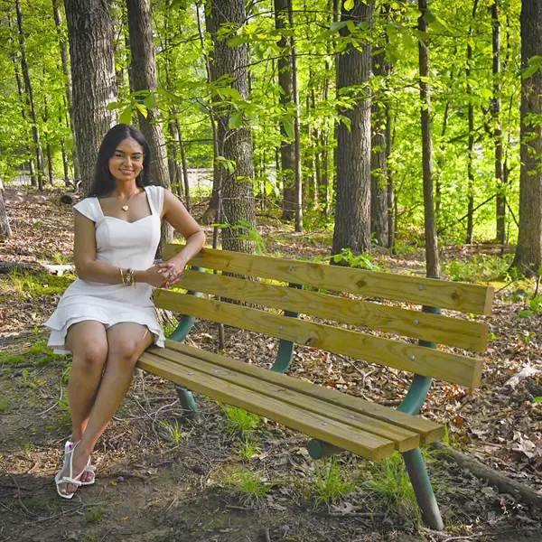 A 2025 graduate sits on one of the benches of the Meditation Trail at USI. 