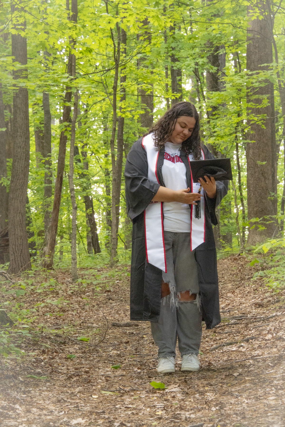 A 2025 graduate stands on USI's Bent Twig Trail 
