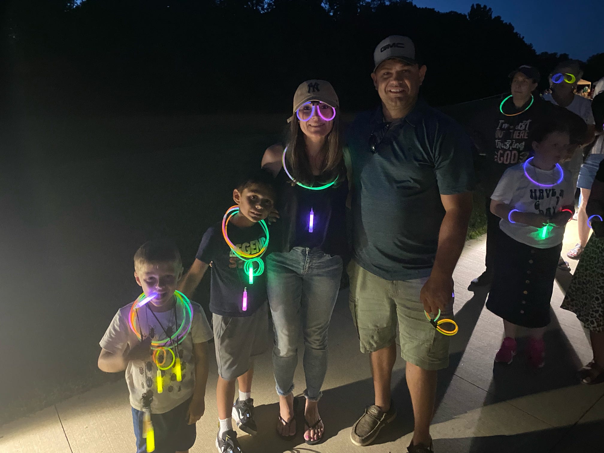 Group of attendees at night wearing glowing necklaces and bracelets.