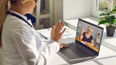 Healthcare professional conducts a telehealth session on her laptop