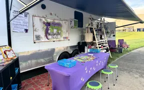 Vendor trailer with crafts and merchandise displayed on tables in front.