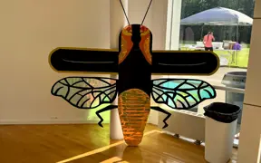 Light-up firefly sculpture with translucent wings displayed indoors on a table.