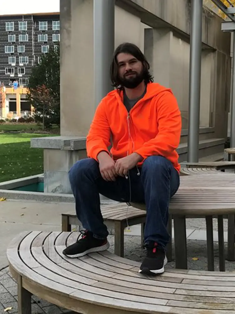 Casual portrait of English graduate Kyle Ellis sitting on a bench