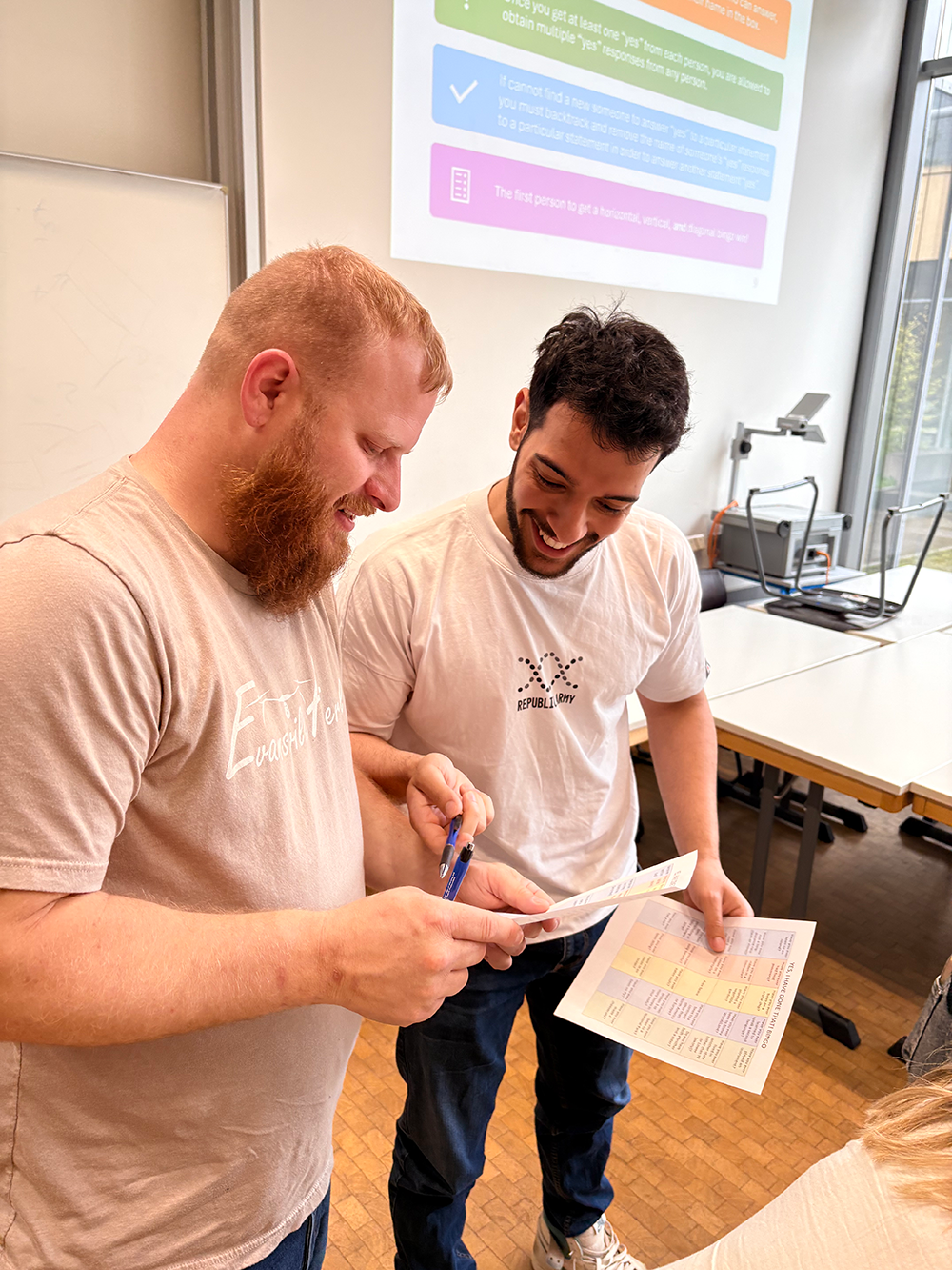 Two smiling students looking at a paper during class