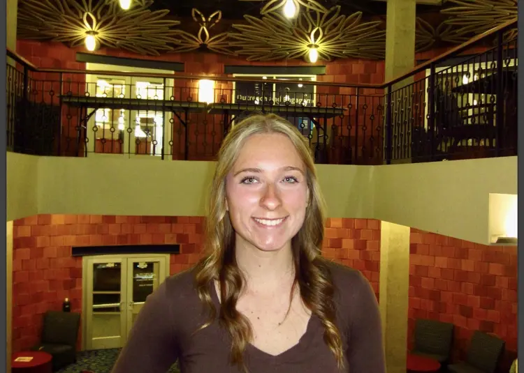 Casual portrait of Ally Patrick standing in the Fireside Lounge at USI
