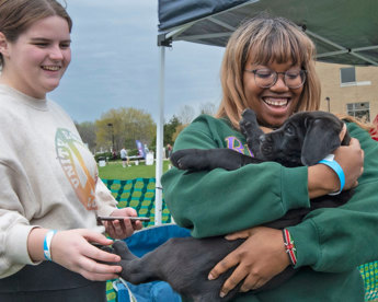 Student holding a puppy during Puppies on the Quad