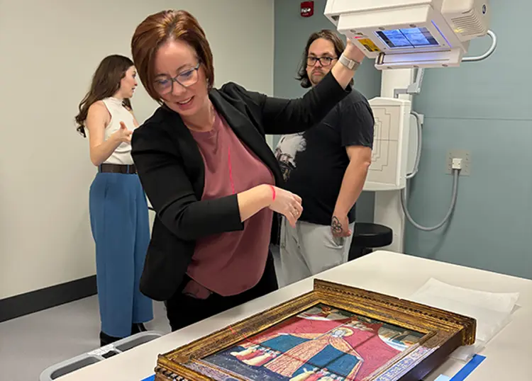 Faculty member adjusting X-ray machine to take images of painting