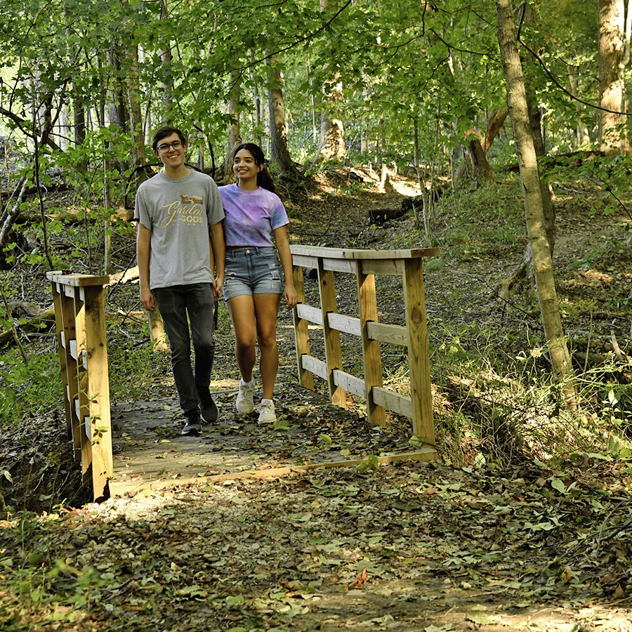 A couple holding hands as they cross a small bridge off of the Beech Trail, which is part of the South Trail complex. 