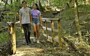 A couple holding hands as they cross a small bridge off of the Beech Trail, which is part of the South Trail complex. 