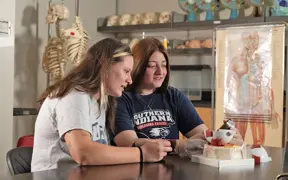 Biology students examine a model of the human eye in a lab