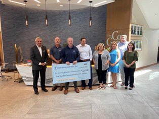 Eight employees holding check