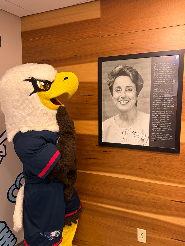 Archie by a framed photo of food pantry founder, Sandra Lawrence