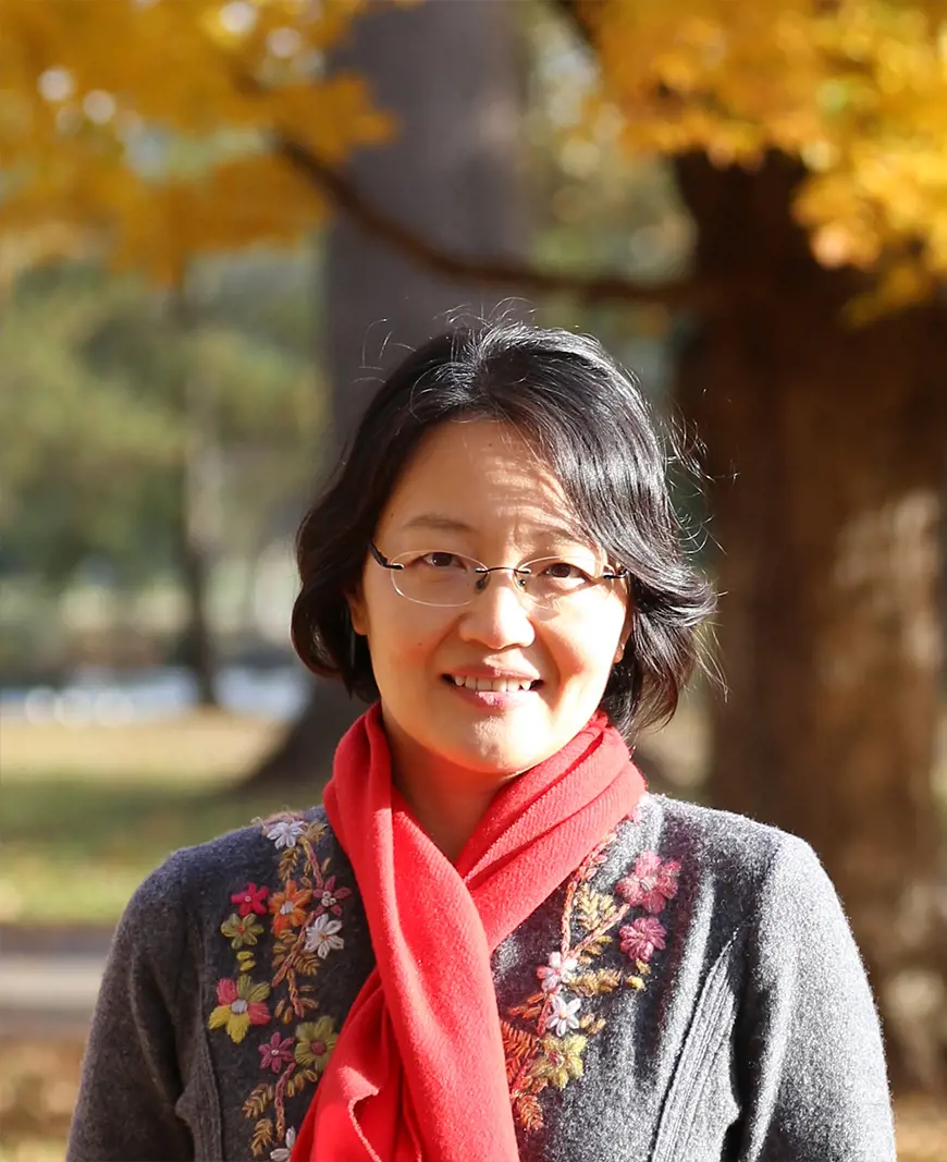 Xinran Hu in front of trees with fall foliage