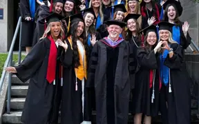 Students in caps and gowns pose with photo with Dr. Craig