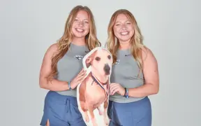 Twin members of USI's tennis team pose with a stuffed animal of their dog during the tennis media day in the photo studio.