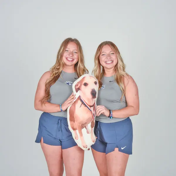 Twin members of USI's tennis team pose with a stuffed animal of their dog during the tennis media day in the photo studio.