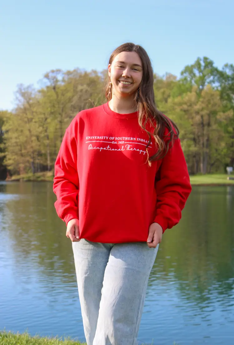 Psychology graduate Jade Browning '25 poses in USI attire in front of Reflection Lake