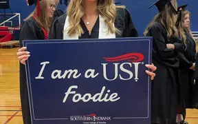 Graduate holding sign that says "I am a USI Foodie"