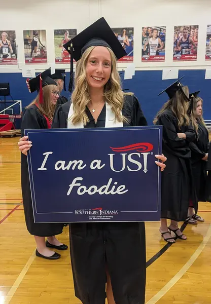 Graduate holding sign that says "I am a USI Foodie"