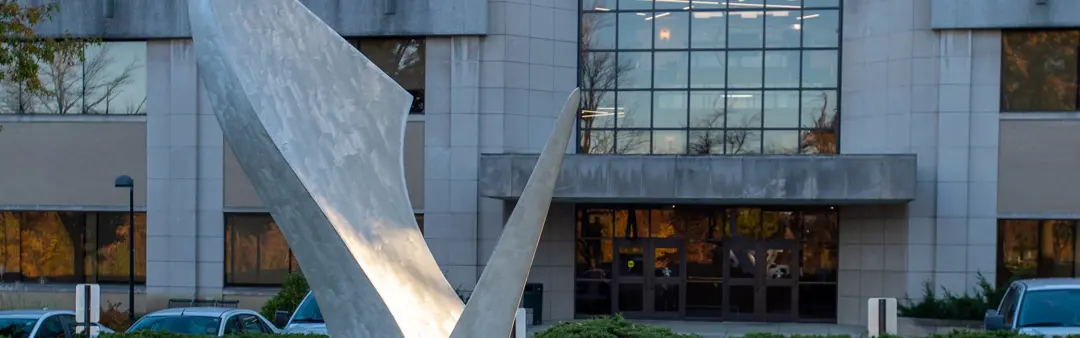 Detail view of the exterior front entrance of the Orr Center with a public art sculpture in the foreground
