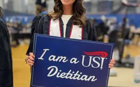 Graduate holding "I am a USI Dietitian" sign