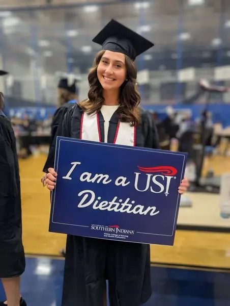Graduate holding "I am a USI Dietitian" sign