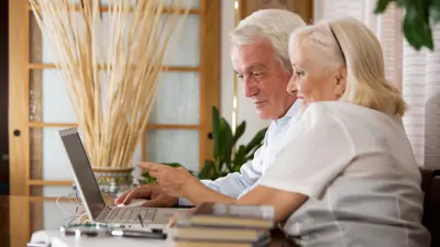 Two people looking at a computer screen and smiling 
