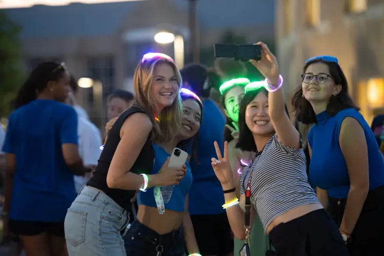 Students posing for a selfie with glow lights