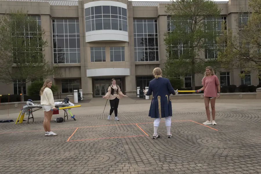 Students being instructed on fencing on brick in front of the Liberal Arts building.