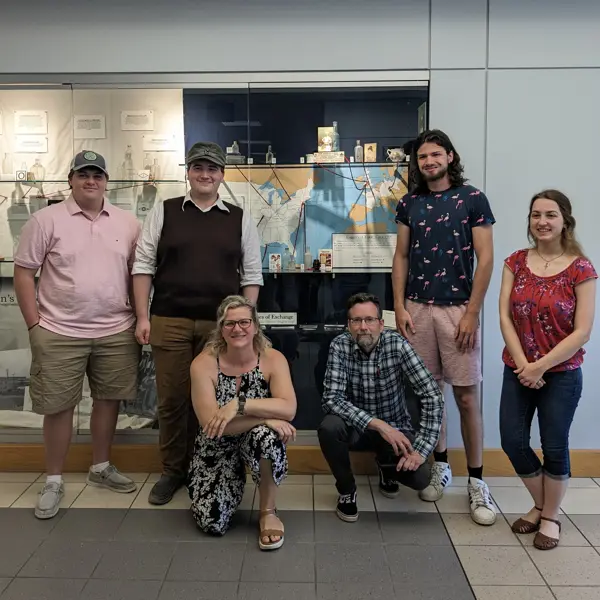 History students pose in front of an exhibit in a display case