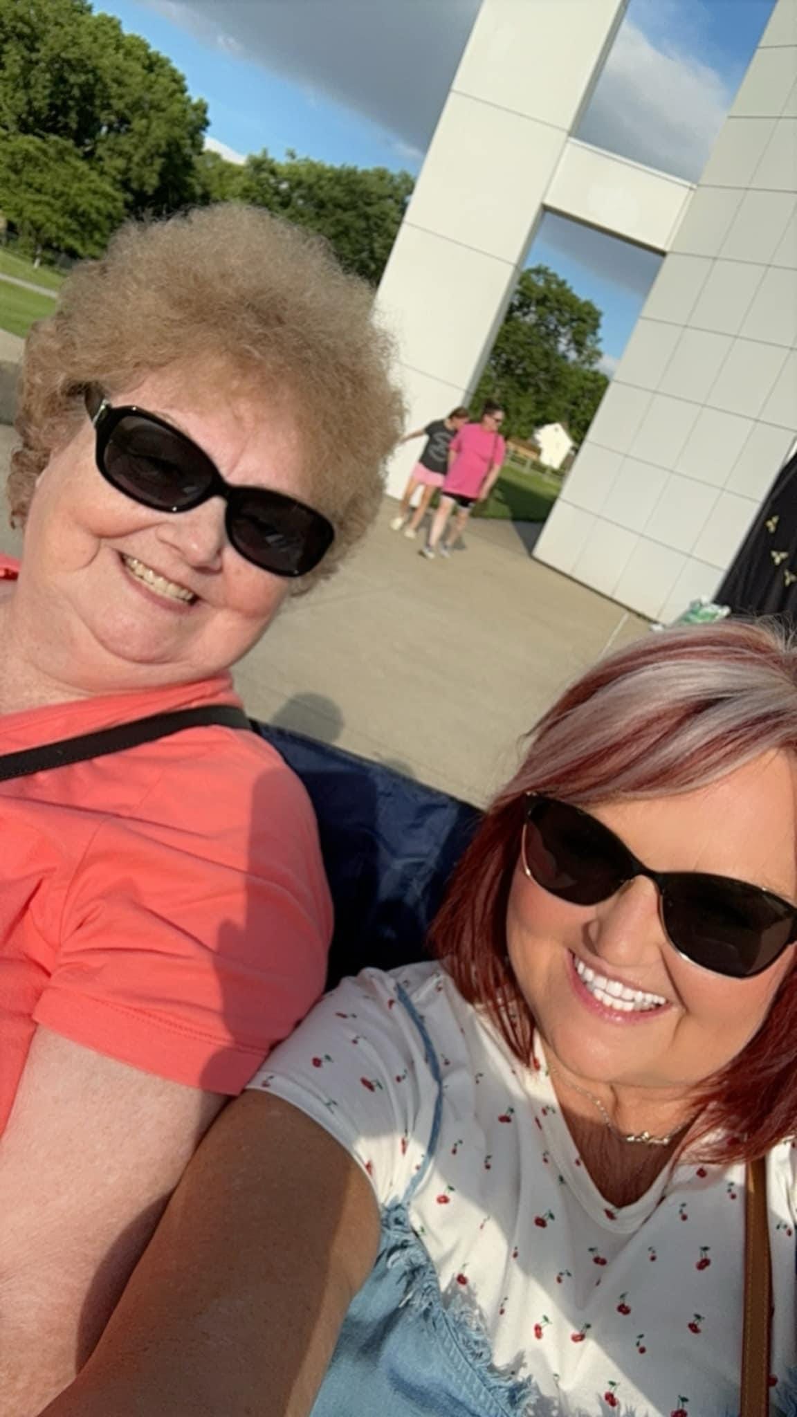 Close-up selfie of two people wearing sunglasses outdoors.