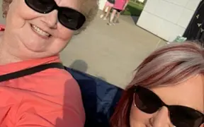 Close-up selfie of two people wearing sunglasses outdoors.