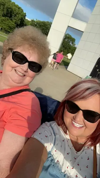 Close-up selfie of two people wearing sunglasses outdoors.