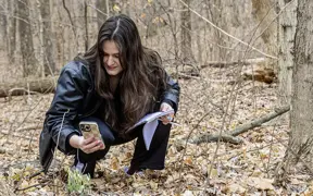 A biology student snaps a photo of a snowdrop found on the Bent Twig Trail for class. 