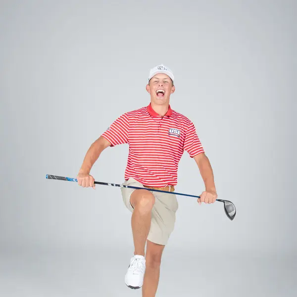 A member of USI's men's golf team pretends to yell and break his club across his knee for his media day photo.