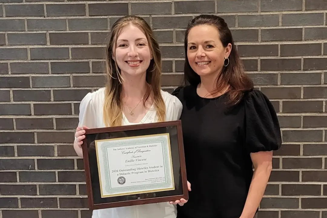Emilie Vincent holding a certificate with Faculty Member Dr. Beth Young