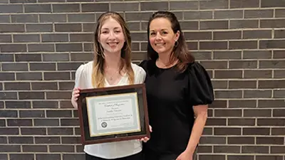 Student holding certificate standing next to faculty member