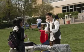 Student watching close up magic outside.