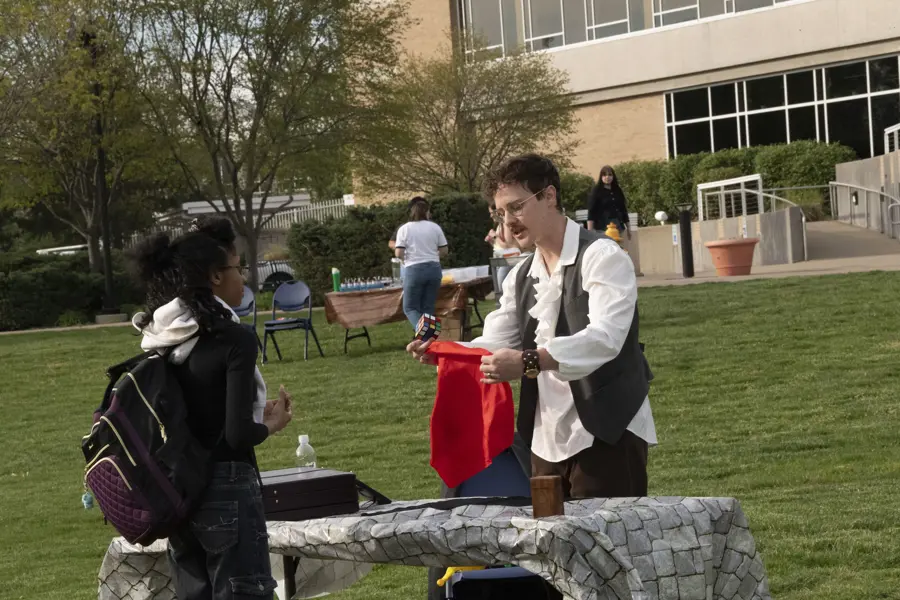 Student watching close up magic outside.