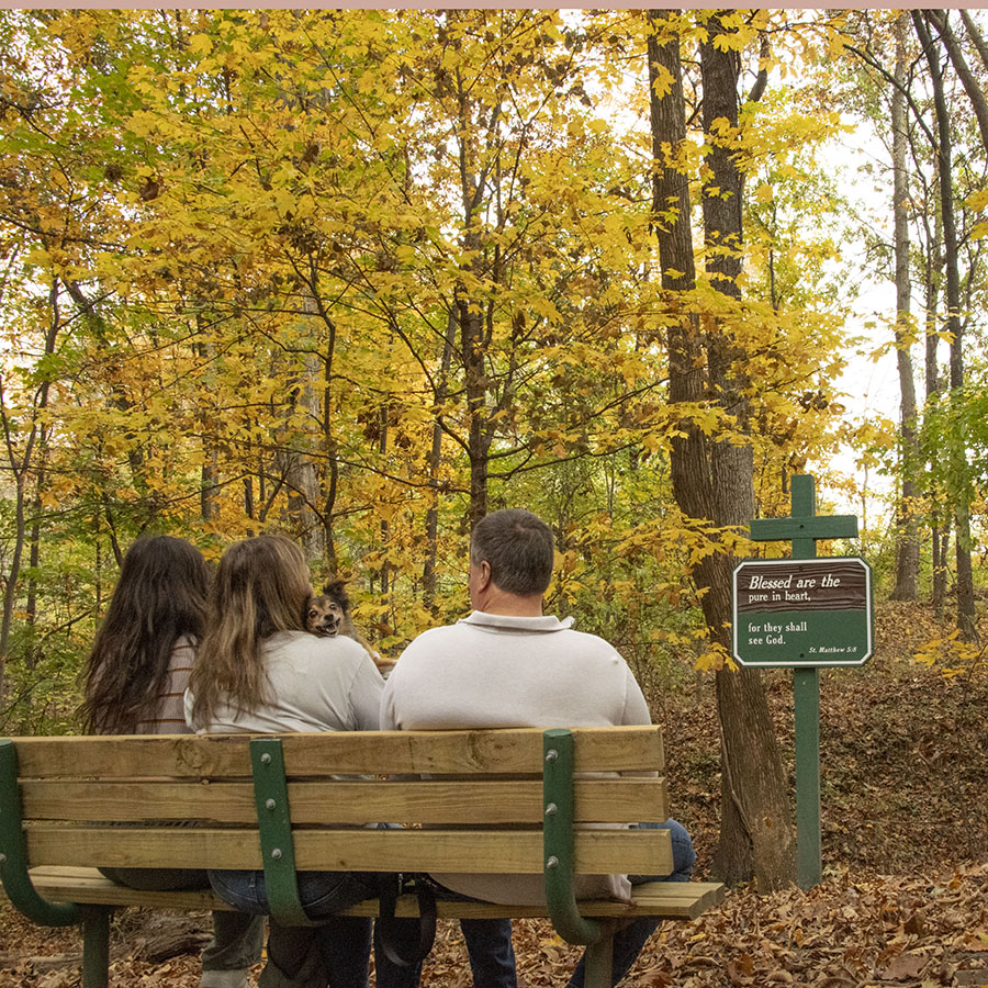A family and small dog, pauses and reflects over the signage found on the Meditation Trail. 