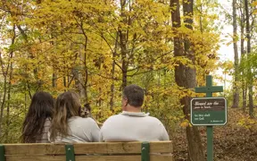 A family and small dog, pauses and reflects over the signage found on the Meditation Trail. 