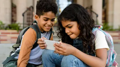Two pre-teens looking at a phone