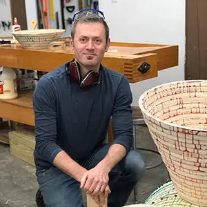 Photo of Travis Townsend in a workshop with wood baskets