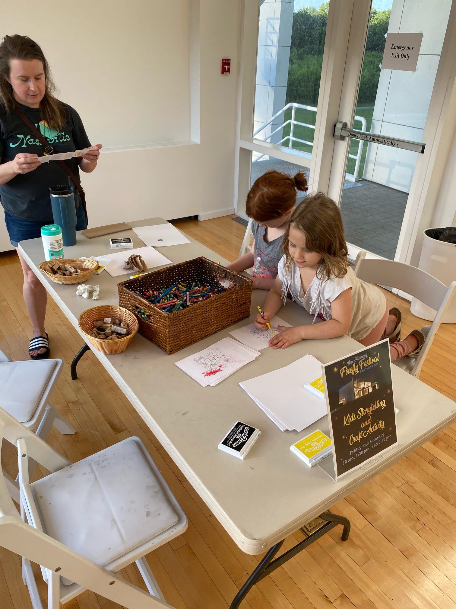 Children drawing at a table with markers and supplies during a hands-on art activity.