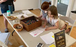 Children drawing at a table with markers and supplies during a hands-on art activity.