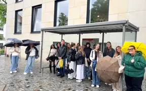 Students waiting for public transportation with umbrellas