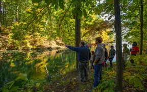 A geology class admires the sandstone lined natural lake on the Bent Twig Trails.